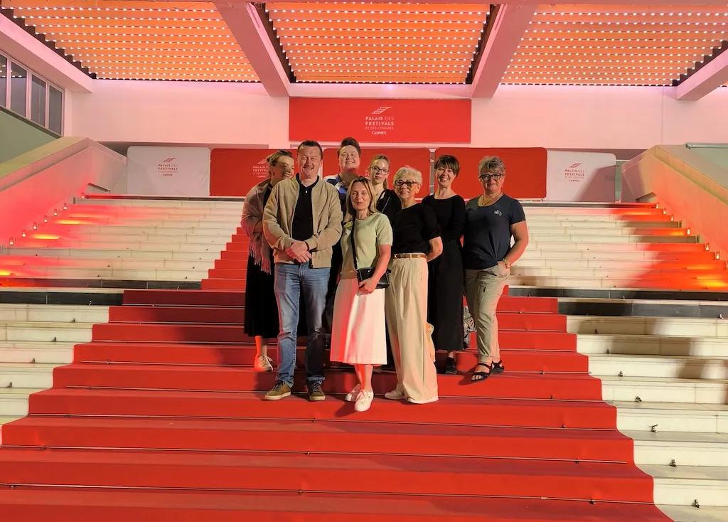 Grupa CoolTurystek pozuje na czerwonym dywanie na schodach Pałacu Festiwalowego w Cannes.